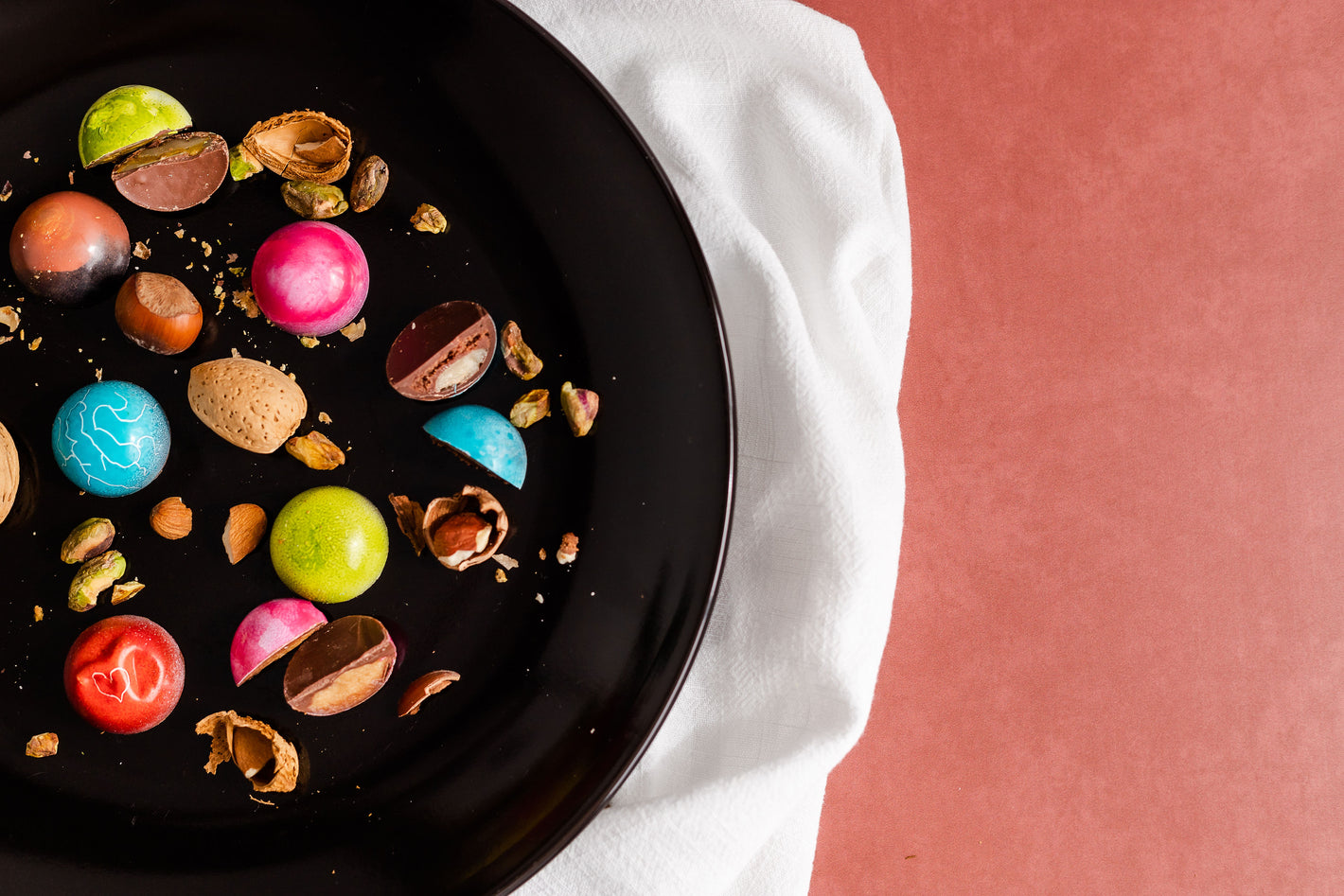 Colorful bonbons on a black plate and a piece of cloth 